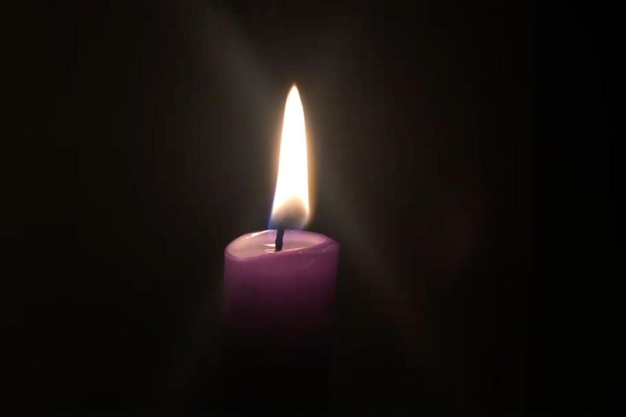 A candle burns in the darkness