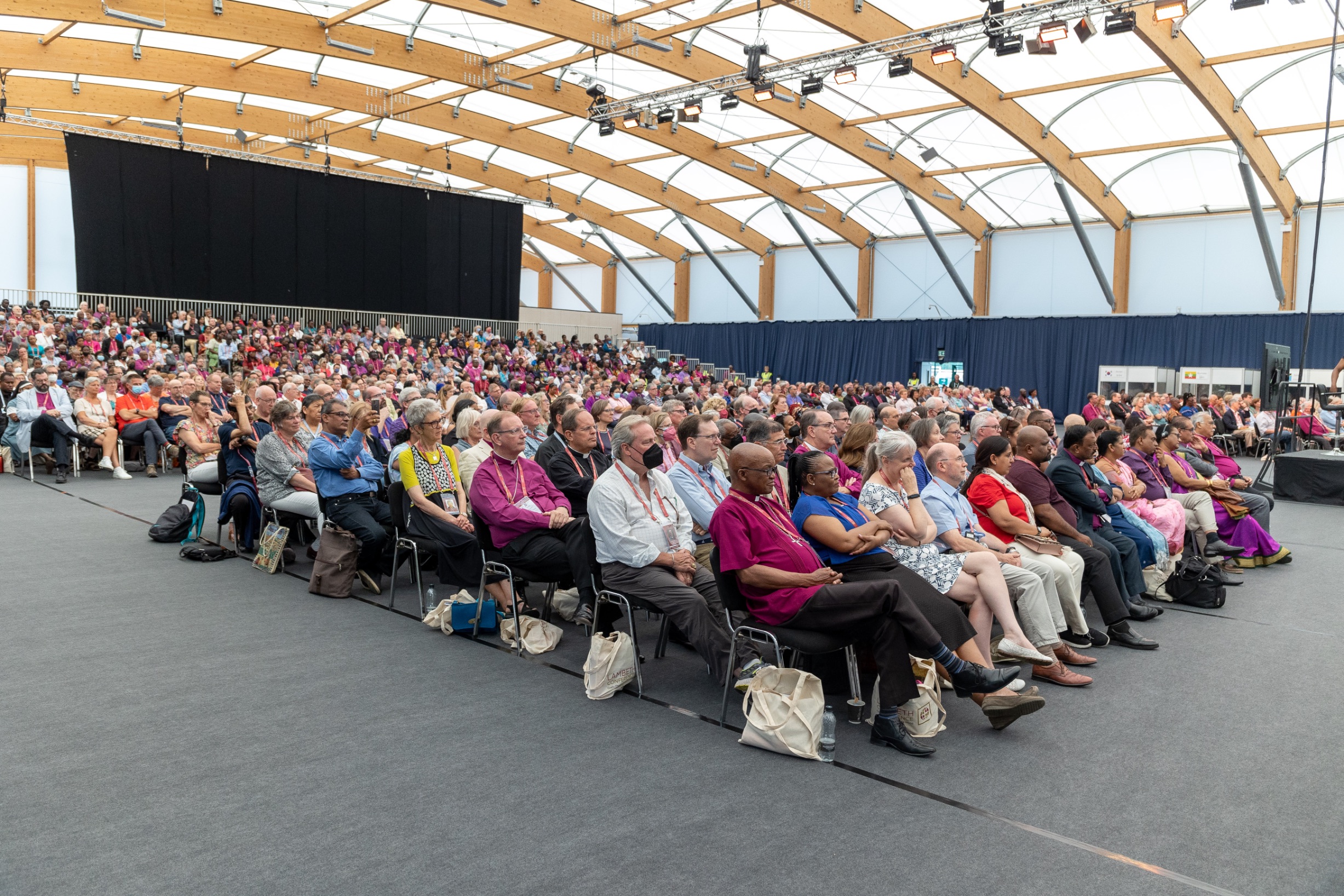 A large room full of Bishops sitting in rows to watch presentations.